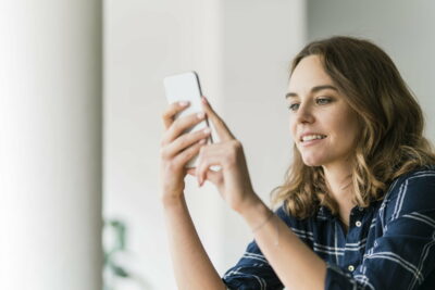 Young woman using smartphone, smiling