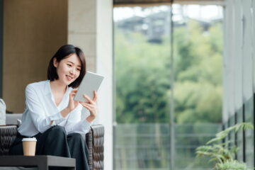 Asian businesswoman using ipad at office window