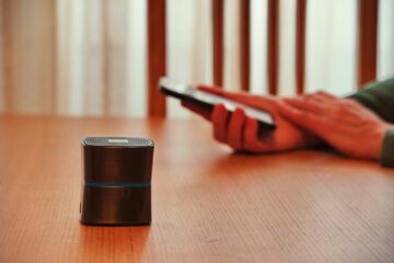 Bluetooth speaker in front of woman's hands holding mobile phone