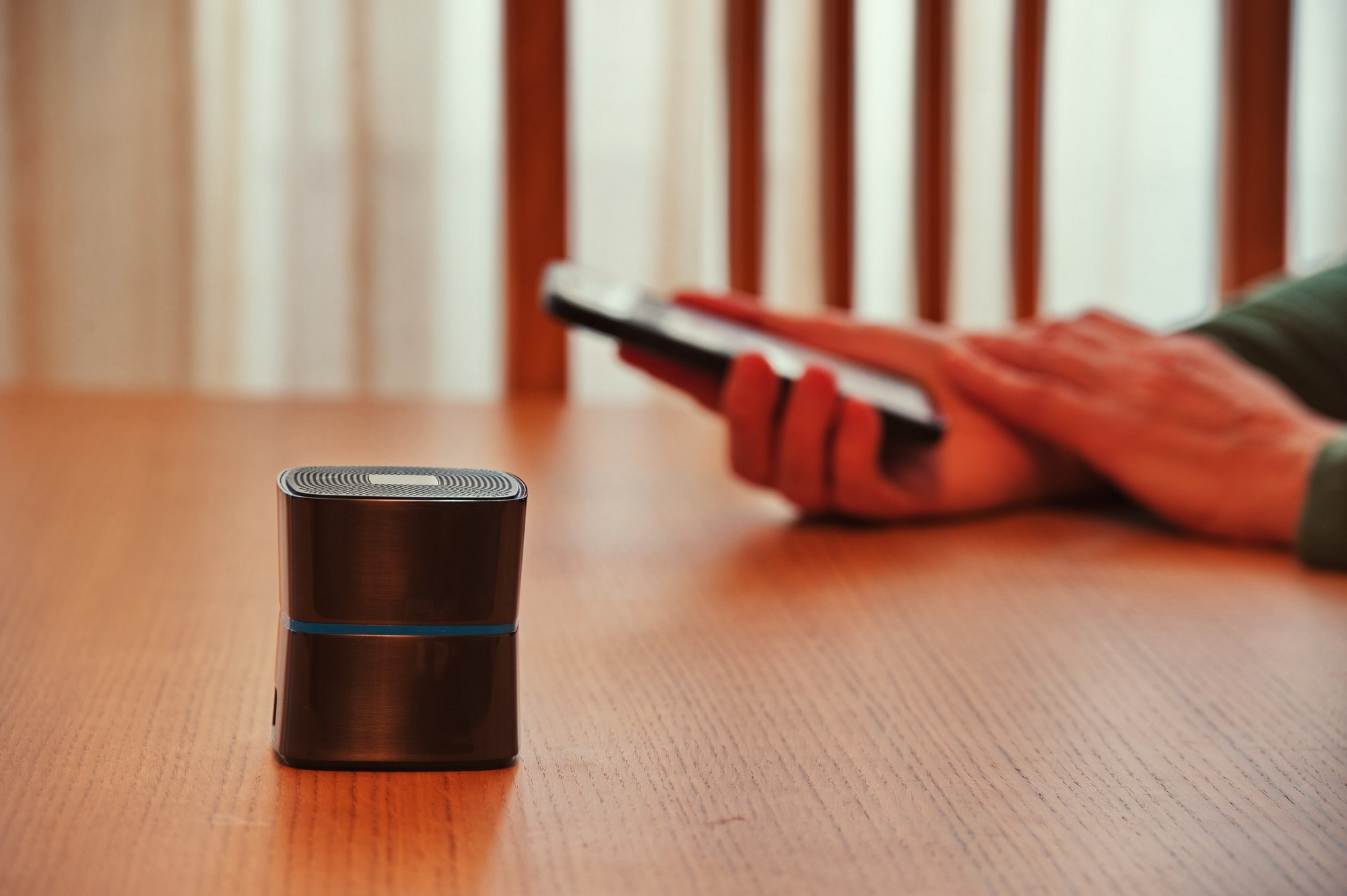 Bluetooth speaker in front of woman's hands holding mobile phone