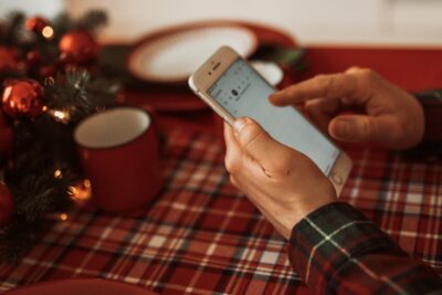 man millennial iphone text chatting at home in christmas atmosphere with laptop