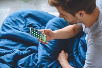 selective focus of young man using iphone at his bed at home