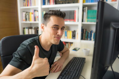 Smiling man in front of the computer.