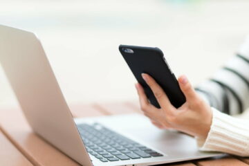 Woman use of smart phone with laptop computer