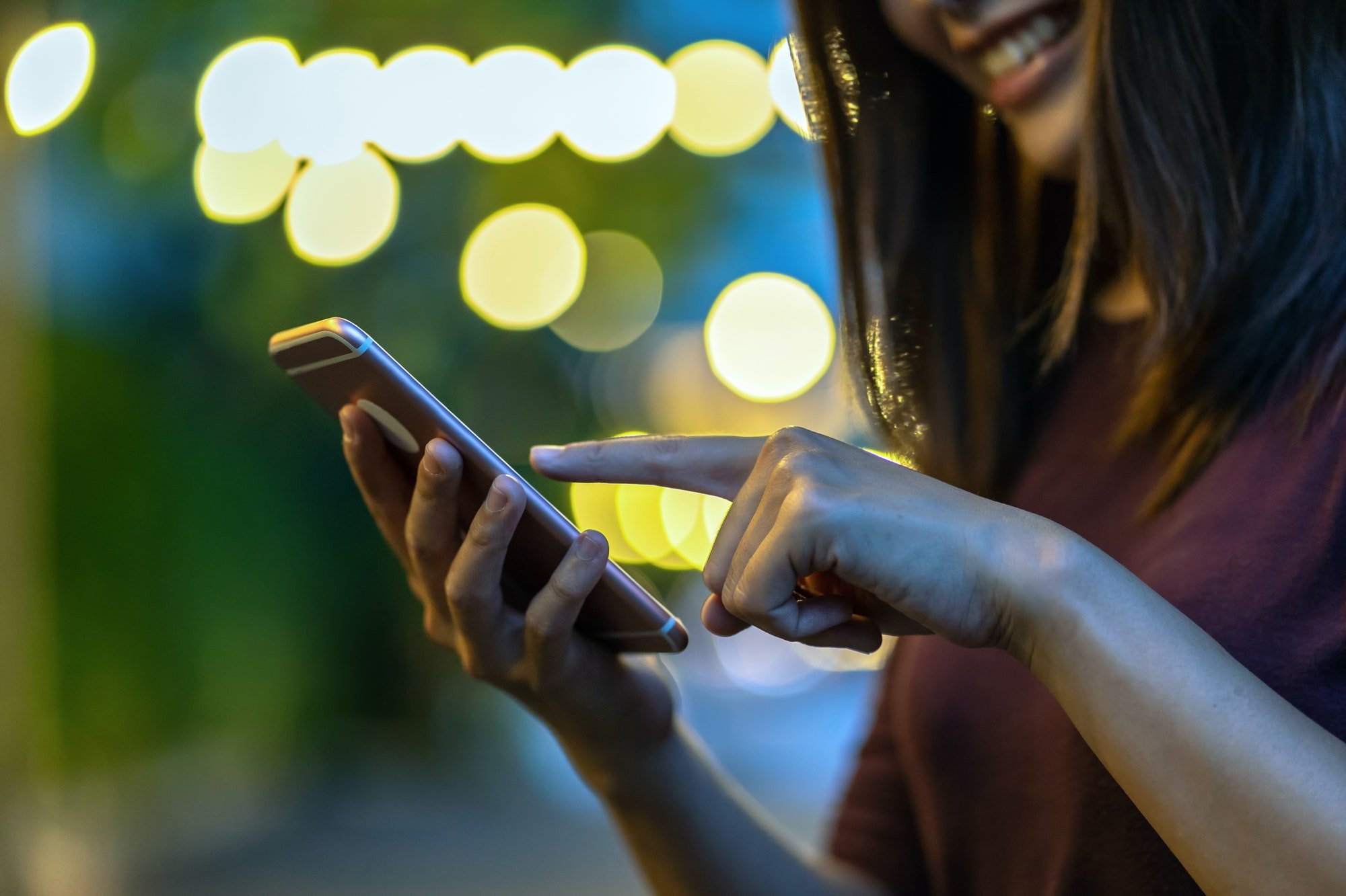 Closeup hand of Asian woman using smartphone and touching screen at outdoor park