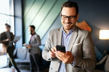 Handsome businessman checking emails on the phone in modern office