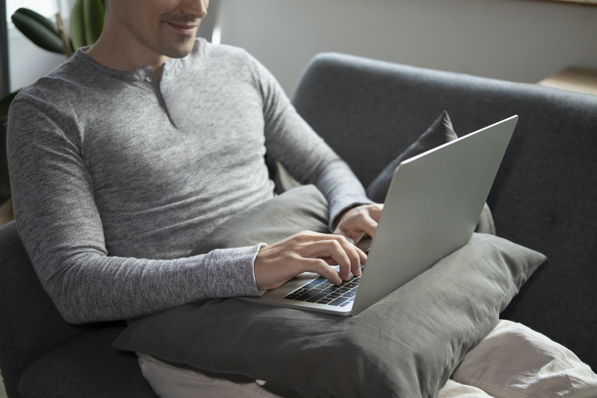 Man in casual clothes browsing internet with computer laptop at home.