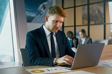 Mature man in a suit typing on a laptop