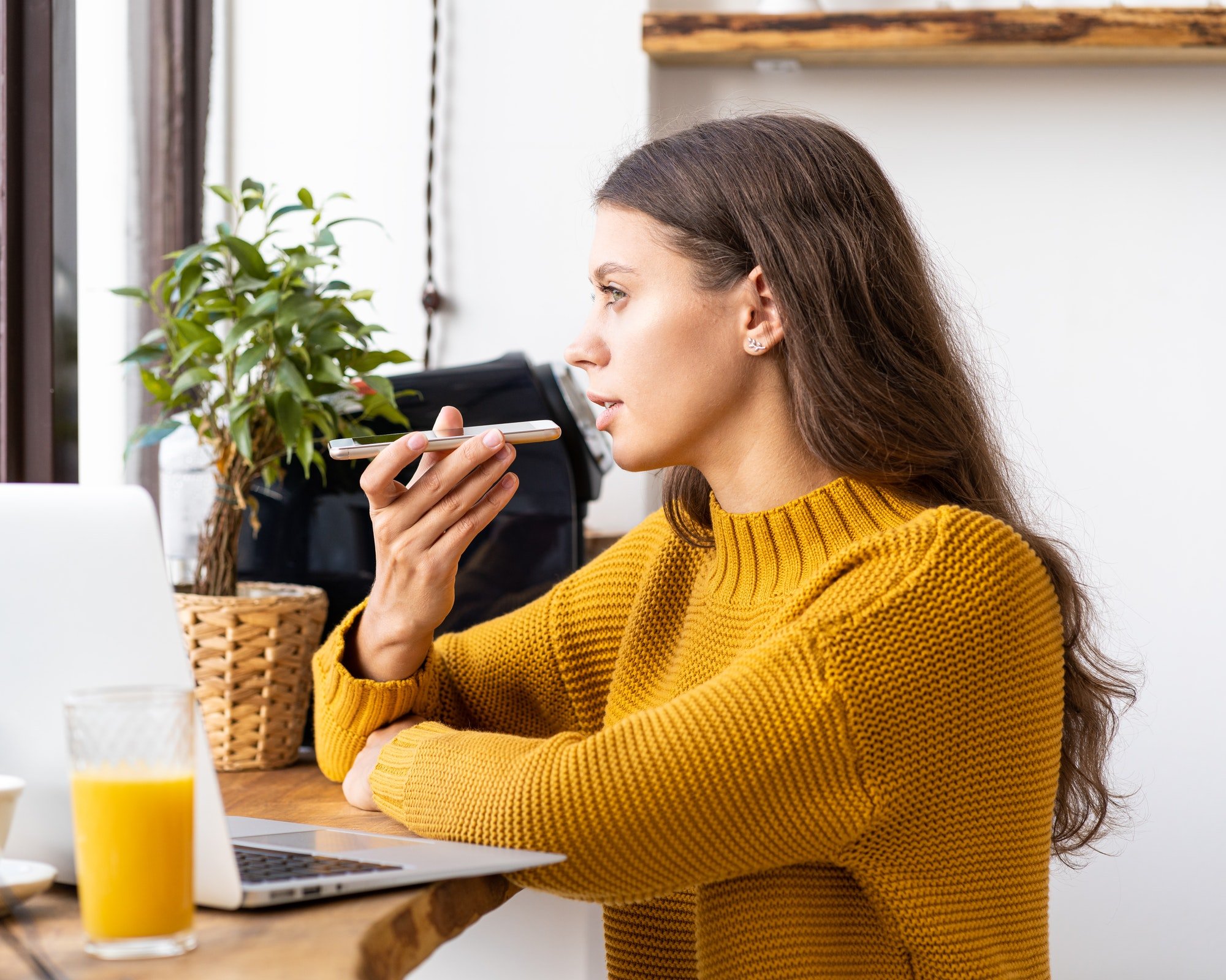 Portrait of positive young woman recording audio message, speaking to microphone