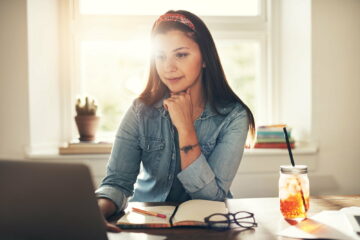 Pretty young woman browsing laptop in office