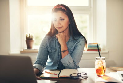 Pretty young woman browsing laptop in office