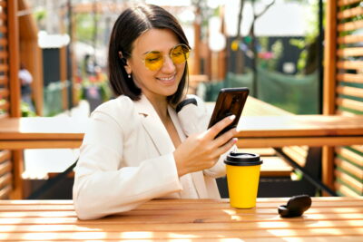 A happy woman laughs while looking at her phone.