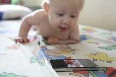 Baby plays with smartphone on bed