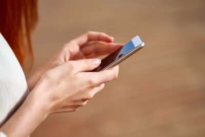 Faceless young woman is holding smartphone and typing