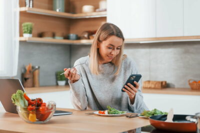 Holding phone. Woman preparing food at home on the modern kitchen