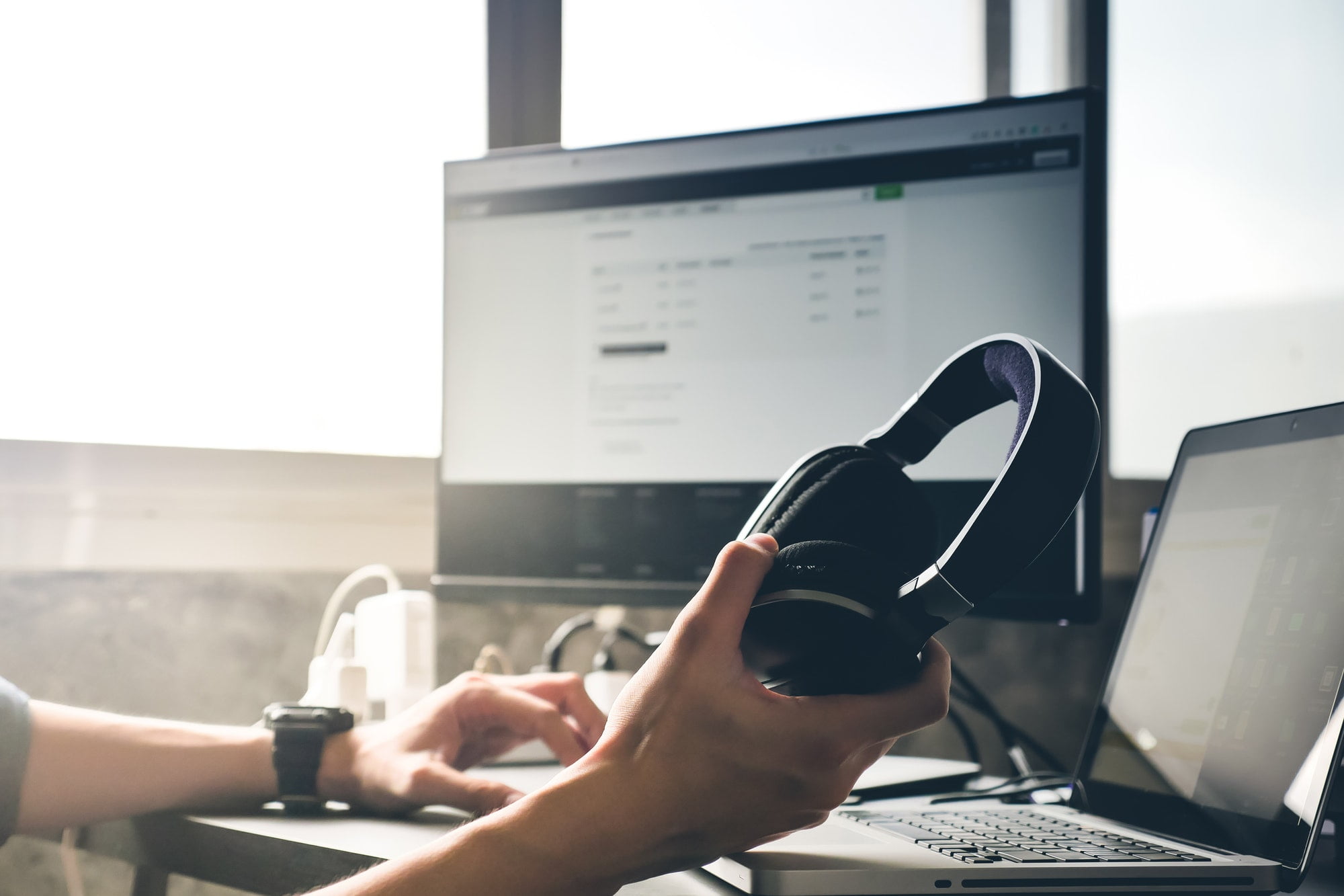 Male hands holding headphones and working on computer