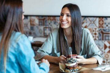 Two beautiful women friends drinking while looking smart phone in the restaurant.