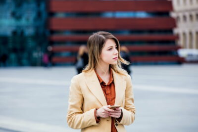 businesswoman typing message by phone on the city square