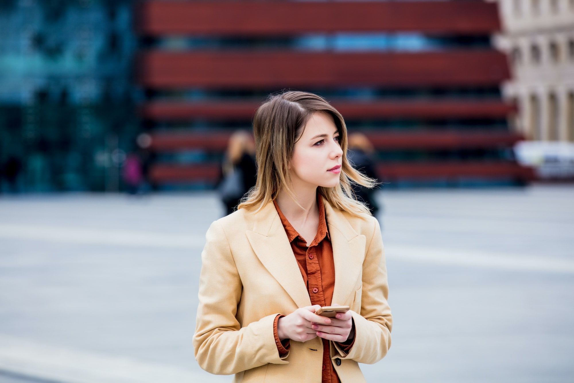 businesswoman typing message by phone on the city square