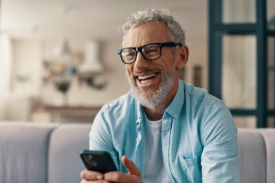 Cheerful senior man phone while sitting on the sofa at home