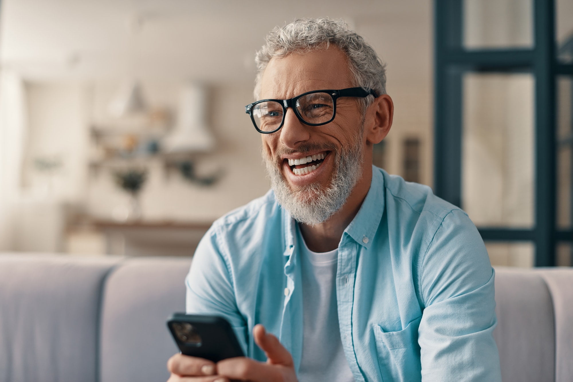 Cheerful senior man phone while sitting on the sofa at home