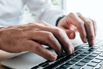 Technical writer typing laptop keyboard, closeup of hands