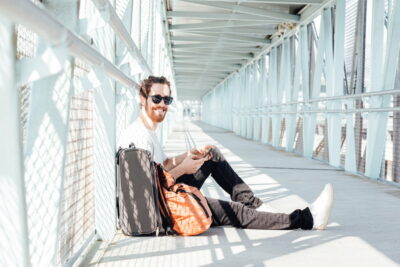 Urban young man talking on smart phone traveling inside in airport. Casual young businessman