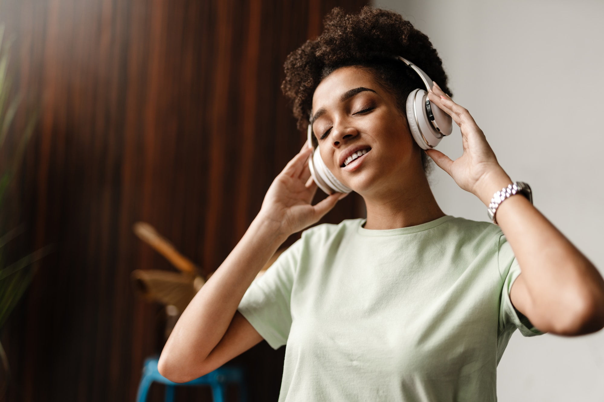 Young black woman listening music with headphones at home