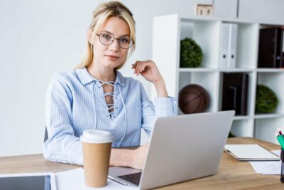 beautiful businesswoman working on startup project in office with laptop and looking at camera