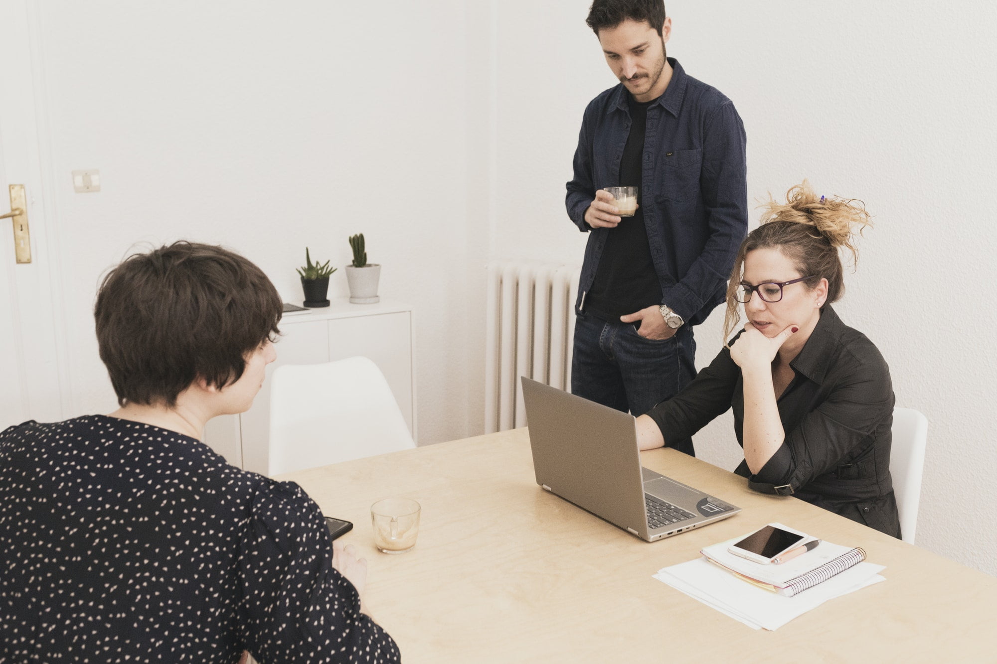 Concentrated young male near lady browsing on laptop at table in office