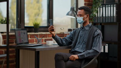 Male secretary holding mobile phone to attend online meeting