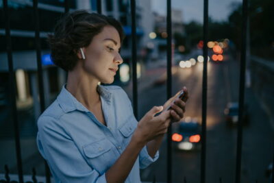 attractive stylish woman walking in street using smartphone