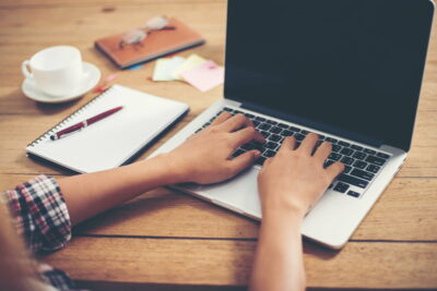 Close-up woman hands typing on laptop in office.