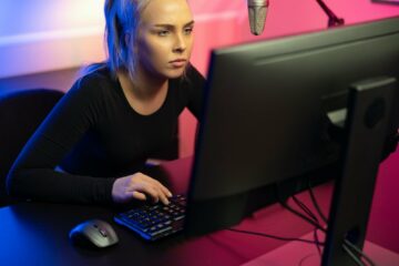 Focused Professional E-sport Gamer Girl with Headset Playing Online Video Game on PC