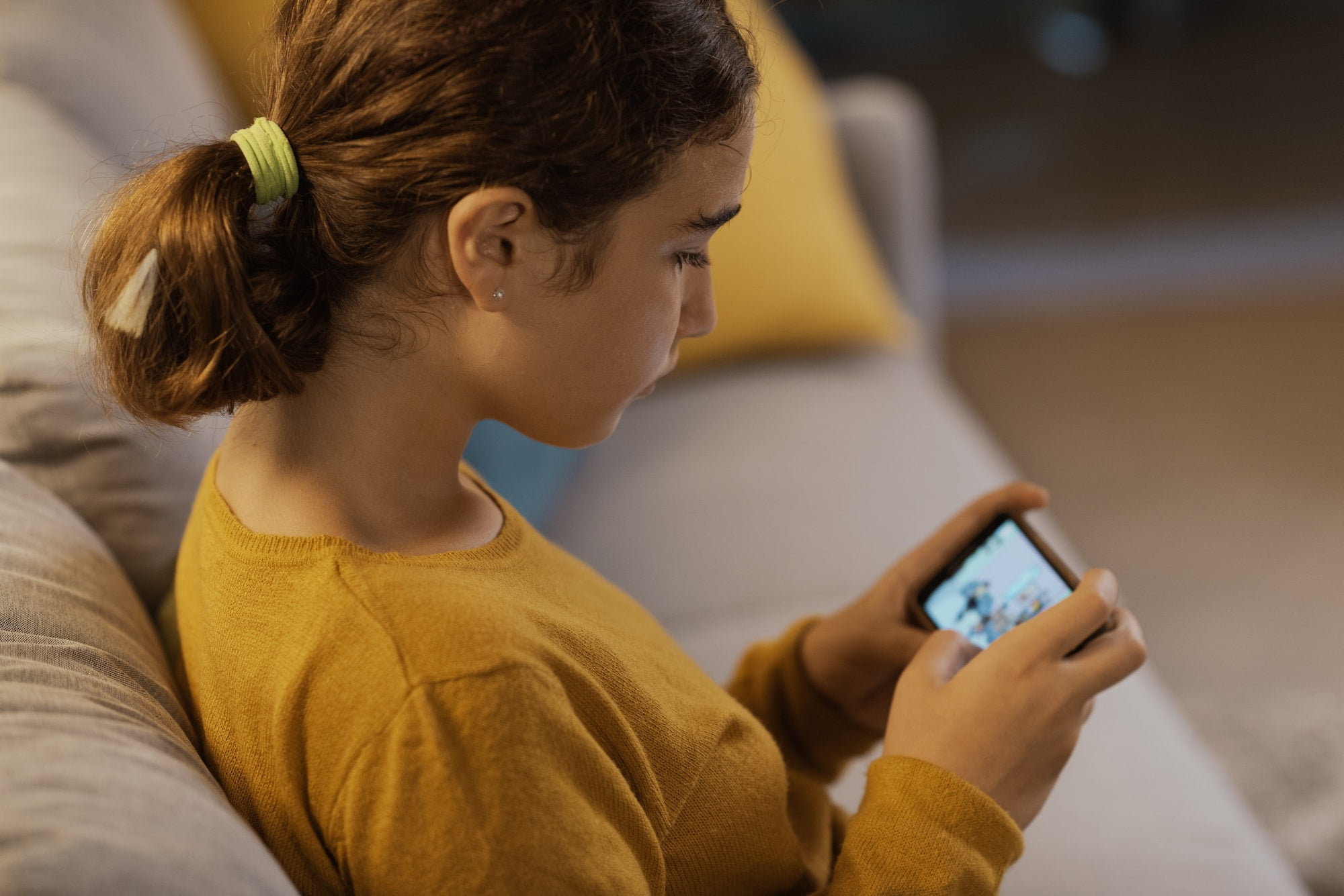 Girl sitting on the couch and using a smartphone