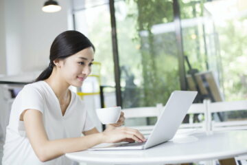 Happy young woman using laptop in coffee shop