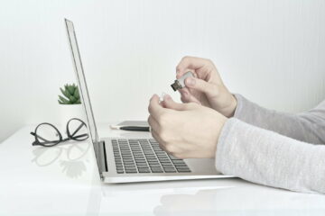 Person opening usb flash next to laptop, Office Work concept on white wall background