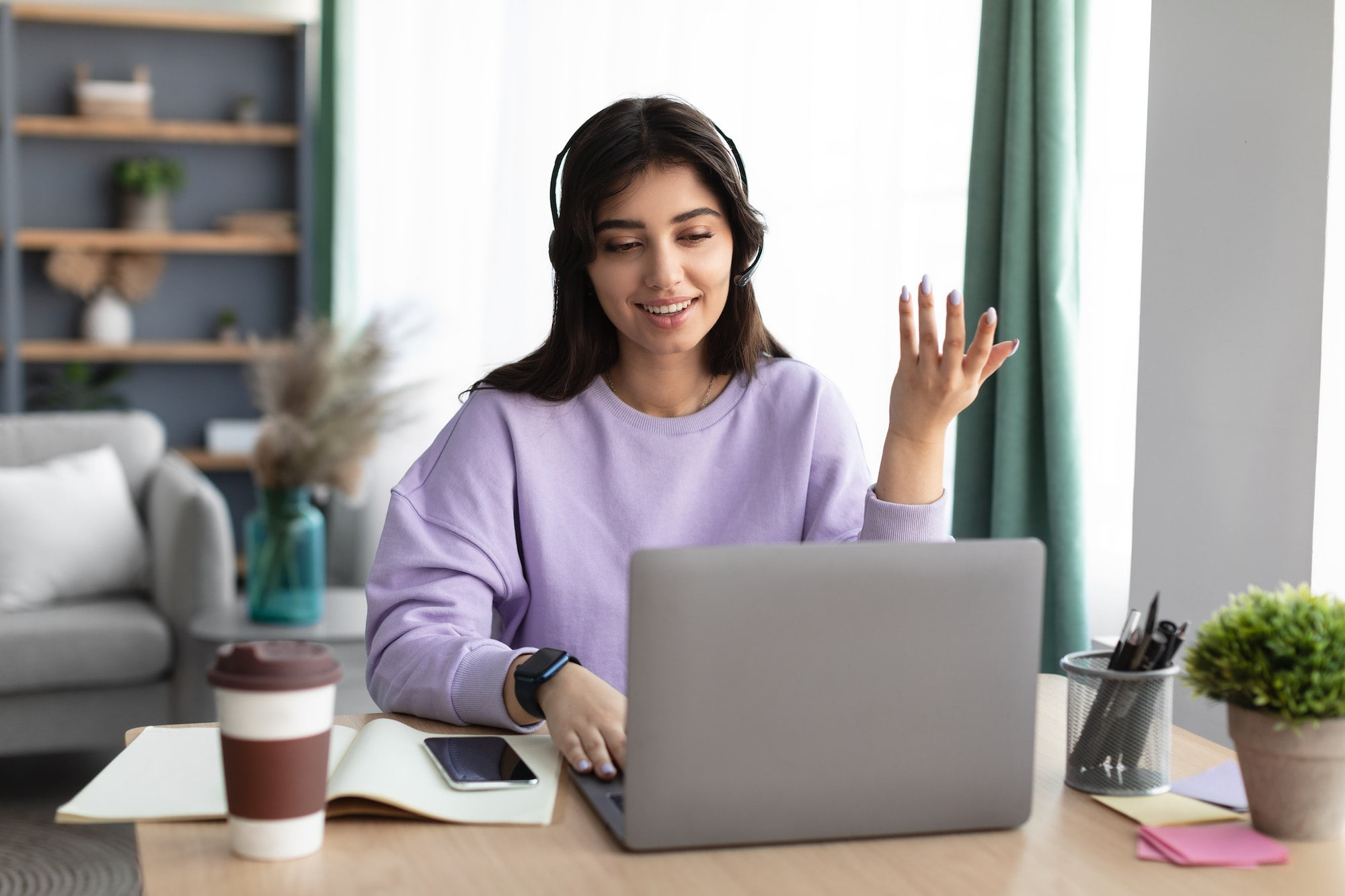 Woman in headphones having videocall using laptop, talking and gesturing