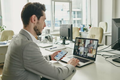 Young businessman communicating with clients online in front of laptop