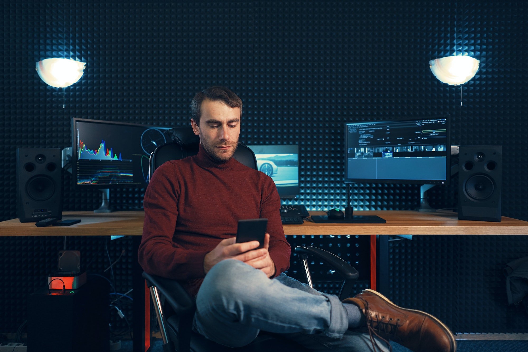 Young man working in the studio using a smartphone and computer.