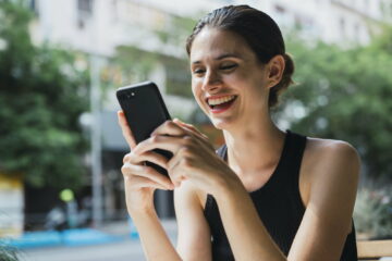 Young woman sitting in cofee shop, using smartphone