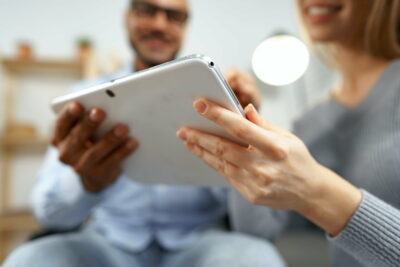 Black man and caucasian woman watching together something on digital tablet