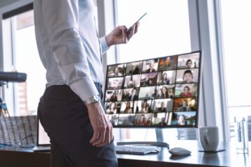 Businessman with his team on video chat computer screen, using phone