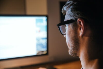 Concentrated man sitting and looking at screen of monitor