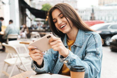 Image of woman playing video game on mobile phone while sitting at cafe