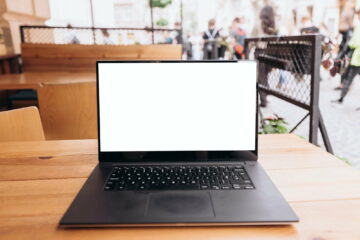 White laptop screen on the table in a cafe on the street