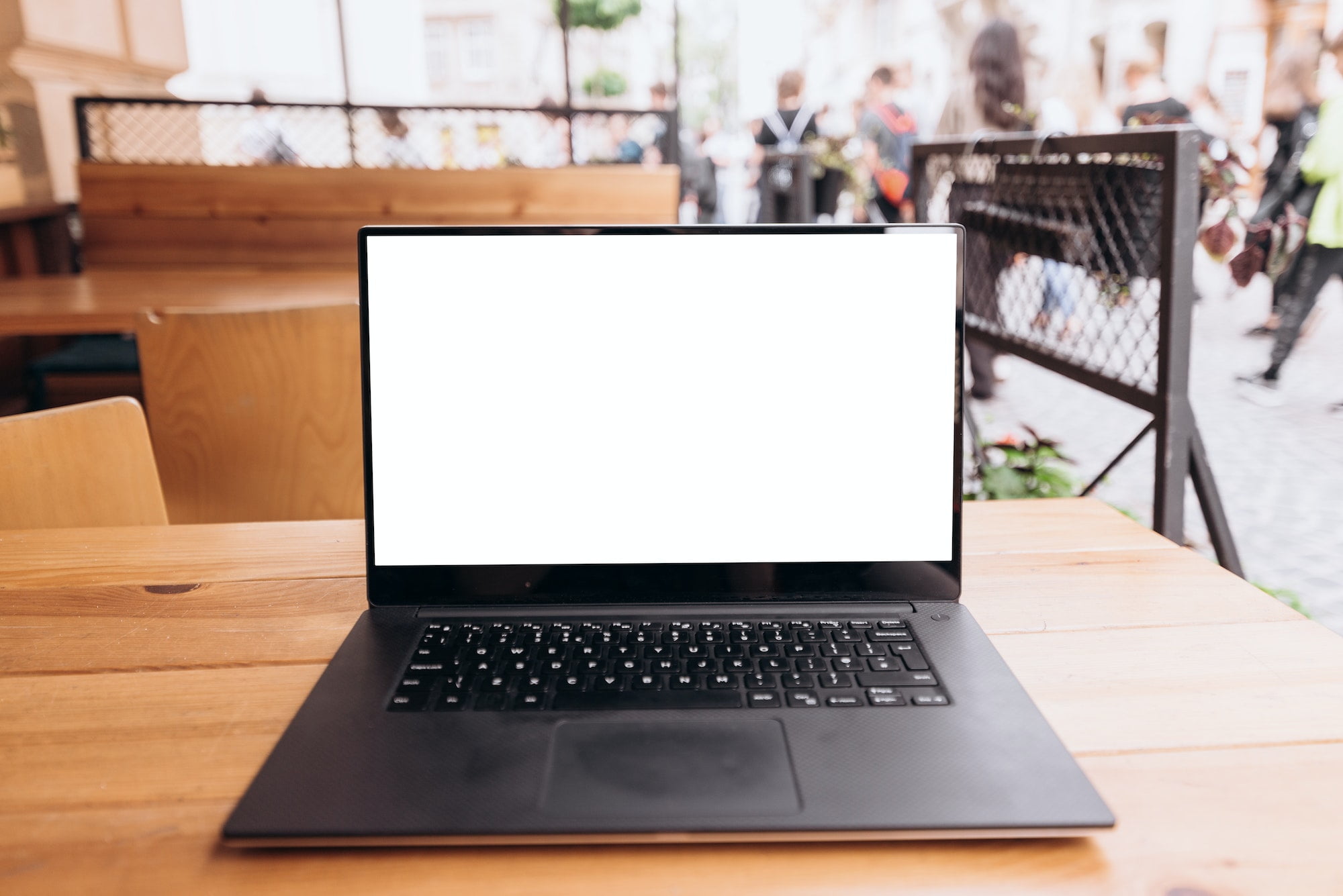 White laptop screen on the table in a cafe on the street