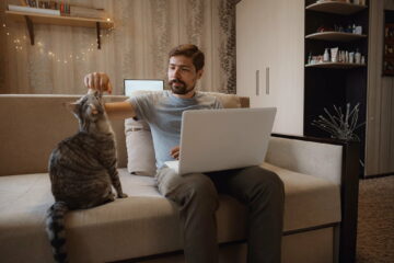 Young attractive smiling guy is browsing at his laptop