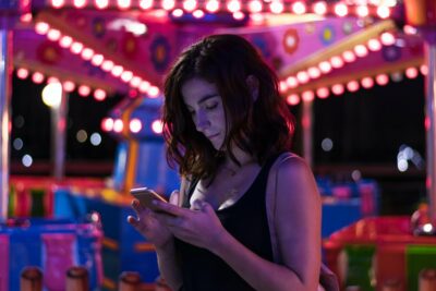 Young woman is looking her smartphone in a fair