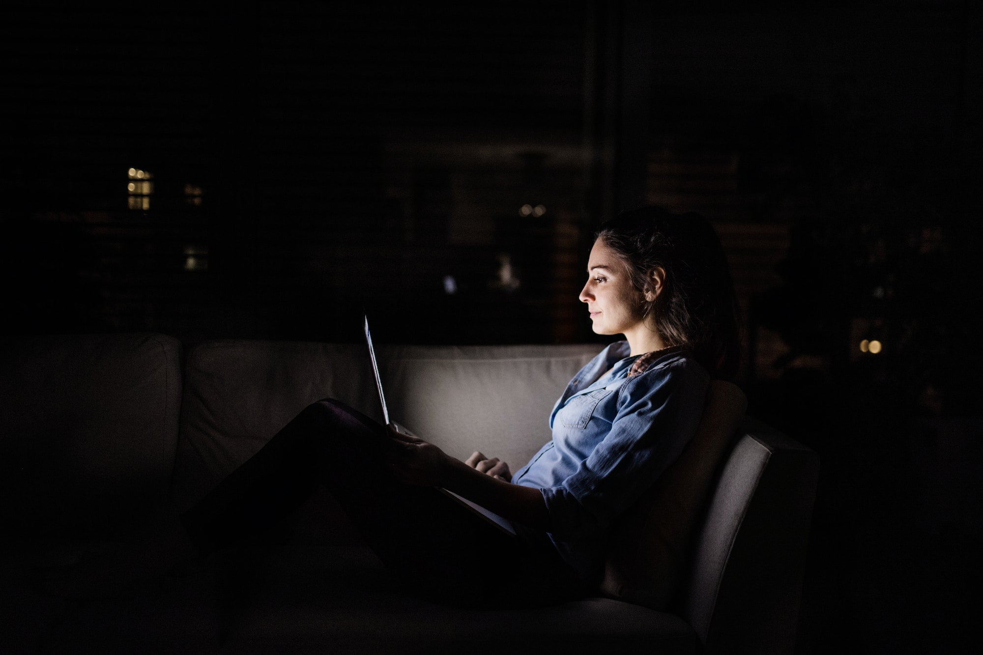 A woman working on a laptop at night at home.